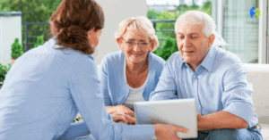 Seniorzy rozmawiają z doradczynią na temat wyboru odpowiedniego ubezpieczenia zdrowotnego, korzystając z tabletu.