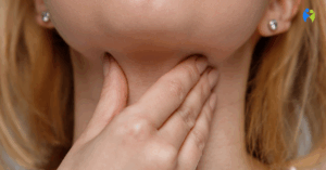 Zbliżenie na osobę, która dotyka swojej szyi w okolicy gardła, co symbolizuje trudności w połykaniu, uczucie przeszkody lub ból związany z dysfagią.